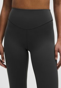Högmidjade leggings i mörkgrått, tillverkade av ett mjukt, elastiskt material. Har en subtil sömdetalj och en minimalistisk design.