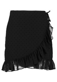 Svart kjol med prickigt mönster, som har en omslagdesign, volangkant och genomskinliga detaljer på sidan. Tillverkad av lättviktsmaterial.