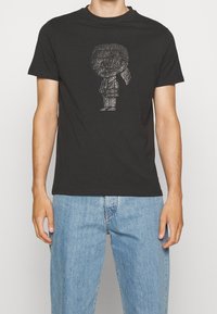 Camiseta de algodón negra con un gráfico de personaje de dibujos animados brillante en el frente, cuello redondo, mangas cortas y un corte relajado.