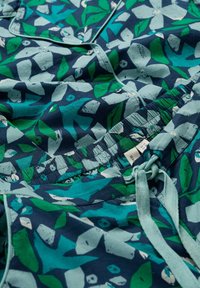 Mustrilis puuvillakangas tumesinises toonis, millel on rohelised ja türkiissinised lehed. Sisaldab elastset vööd, millel on pael ning nööbikaunistused.