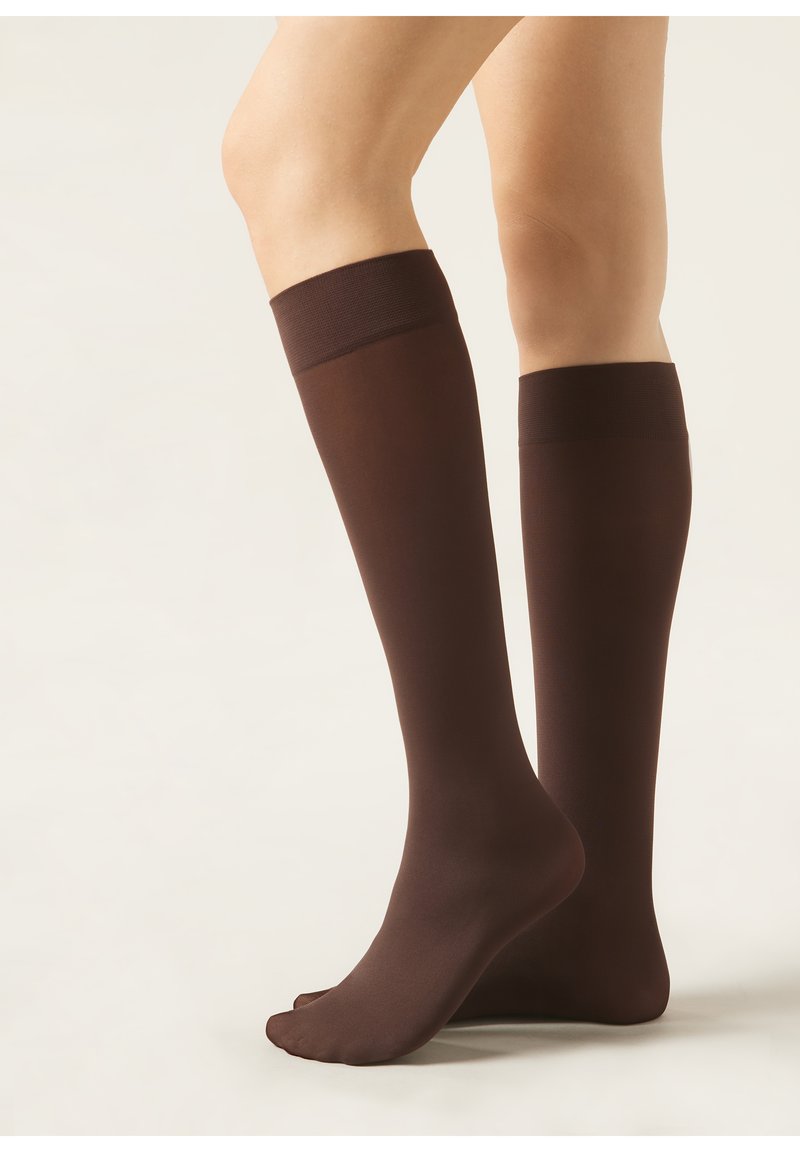 Calze marroni alte fino al ginocchio realizzate in un materiale liscio, con un colore uniforme, che presentano una fascia a coste scura nella parte superiore e un design della punta senza cuciture.
