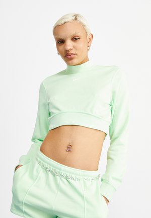 Cropped dukserica u mint zelenoj boji i odgovarajući trenirci od mekog materijala; dukserica ima visoki ovratnik i Nike logo; trenirci imaju detalj s lancem.