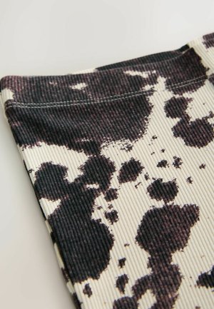 Geribbelde stof top met een zwart-wit koeienprintpatroon, met duidelijke texturen en omrandde naden aan de randen.