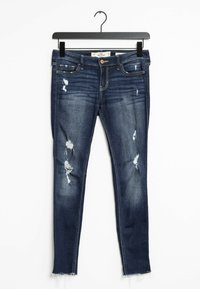 Mörkblå denim skinny jeans med slitna partier och fransad fåll, med en klassisk femfickdesign och knappstängning.