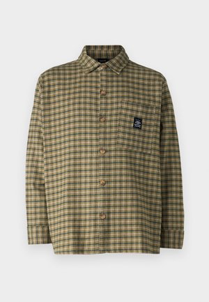 Green and brown plaid shirt, long sleeves, collar, button closure, featuring a pocket with a small logo patch. Textured fabric.