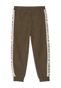 Olivgrüne Jogginghose mit schmal zulaufendem Bein, ausgestattet mit seitlichen Streifen in Creme und blauer Schrift. Hergestellt aus weichem, strukturiertem Stoff mit elastischen Bündchen.