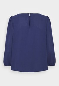 Navy blue blouse with long puff sleeves, soft fabric, straight cut, and a rear keyhole opening with a small metal closure.