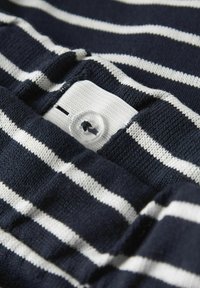 Námorníckomodrá a biela pruhovaná látka s detailom gombíka. Štruktúra je pletená, s bielou štítkou a viditeľným šitím pri gombíku.