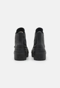 Bottes chelsea en cuir noir avec un bout arrondi, des panneaux latéraux texturés et une semelle en caoutchouc ; elles présentent un badge logo à l'arrière et sur la languette.