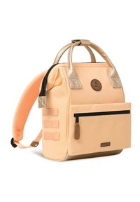 Pfirsichfarbene Canvas-Rucksack mit metallic-goldenen Akzenten, Tragegriffen oben und verstellbaren gepolsterten Schulterriemen. Verfügt über eine vordere Reißverschlusstasche und Seitenriemen.