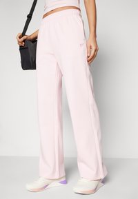 Pink wide-leg sweatpants made of soft material, featuring an elastic waistband and a small logo embroidered in a contrasting color.