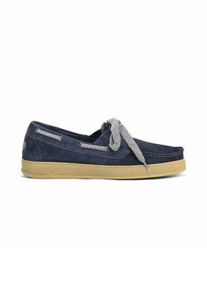 Mocassino in camoscio blu navy con suola in gomma beige e lacci in tessuto grigio annodati a fiocco su sfondo bianco.