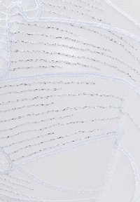 Biely textil s jemným vyšívaným vzorom a striebornými akcentmi, ktorý vystihuje štruktúrované línie a krivky.