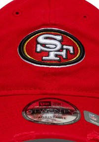 Rød baseballcaps med brodert San Francisco 49ers-logo og en rund justerbar tag som indikerer "New Era 9TWENTY."