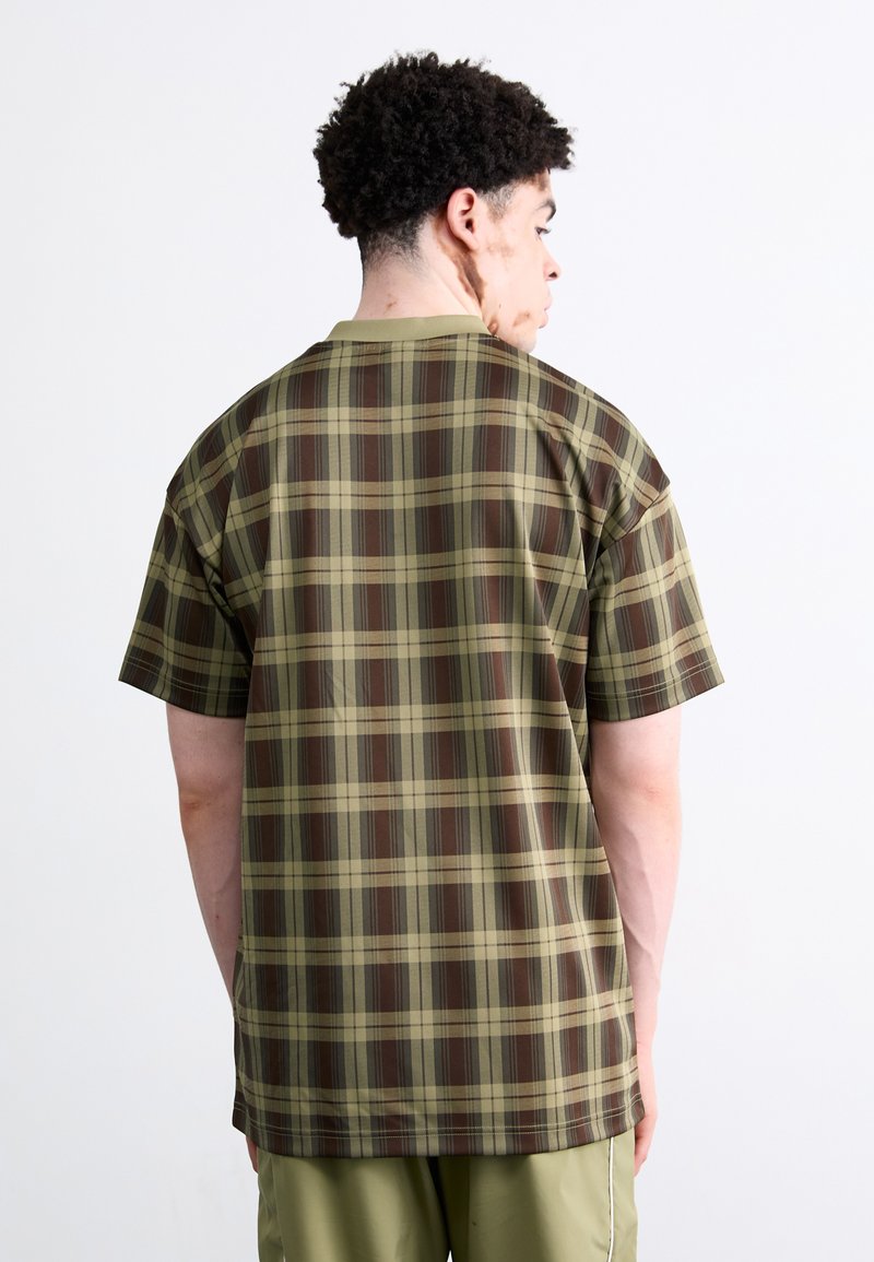 Koszula z krótkim rękawem w zielono-brązową kratę, wykonana z lekkiego materiału, o luźnym kroju i okrągłym dekolcie.