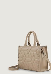 Sac à main beige avec un design matelassé géométrique, doté de poignées doubles et d'une bandoulière amovible. Fabriqué en cuir lisse.
