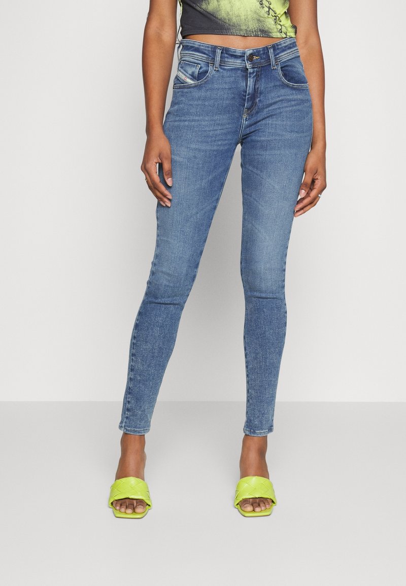 Slim fit jeans i medelblå denim med lätt blekning. Matchat med ljusgröna, strukturerade slip-on sandaler.