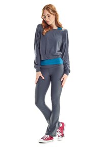 Graues Langarmshirt mit blauen Akzenten, kombiniert mit dunkelgrauen, eng anliegenden Hosen und roten Sneakers. Glatte Textur mit lockerer Passform.