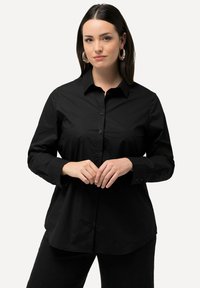 Camicia nera con bottoni, maniche lunghe, colletto classico e orlo curvo. Presenta un tessuto morbido e bottoni neri abbinati.