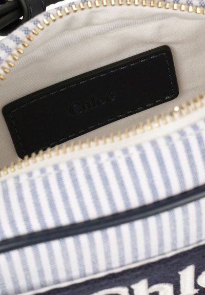Pochette in tessuto a righe con zip dorata, etichetta in pelle nera all'interno incisa con "Chloé" e fodera color crema.