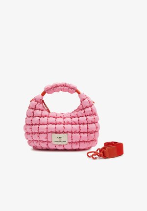 Pink quilted handbag with puffed texture and a short handle, a beige brand label, and a detachable red shoulder strap beside it.