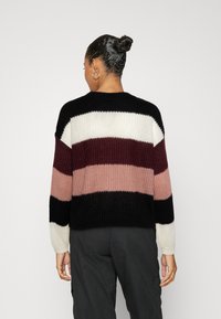 Gebreide trui met horizontale strepen in zwart, wit, bordeauxrood en blush. Ontspannen pasvorm met ronde hals en lange mouwen.