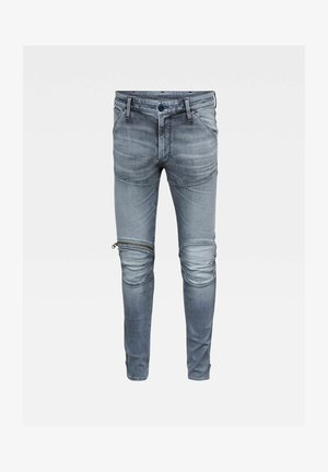 Vaqueros slim fit de mezclilla gris con paneles en las rodillas y un detalle de cremallera horizontal en el muslo izquierdo.