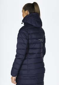 Navy puffer jacket with a hood, featuring quilted sections, elastic cuffs, and a zippered front. Logo printed on the back near the collar.