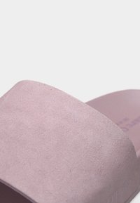 Απαλή ροζ σουέντ σανδάλι slide με φαρδιά λουρί και ανοιχτό δάχτυλο, φωτογραφημένο σε λευκό φόντο.