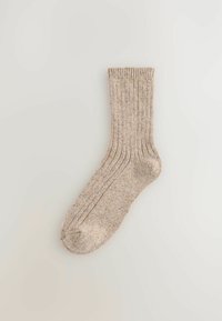 Beige rebrasti čarapa napravljena od teksturirane tkanine, s pojačanim prstom i manžetom, s suptilnim flekovima boje kroz cijelu čarapu.