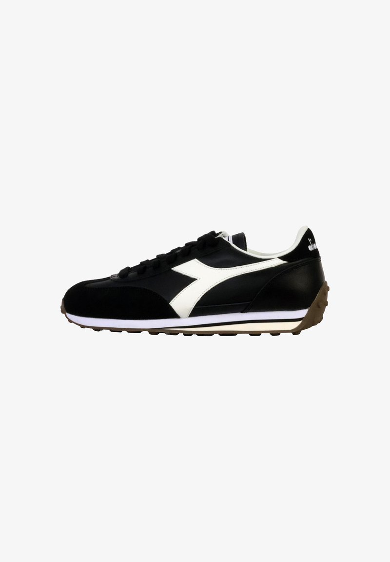 Scarpa sportiva nera con accenti bianchi, caratterizzata da una tomaia in suede e sintetico, chiusura con lacci e una suola in gomma testurizzata.