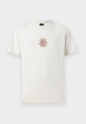 Tricou din bumbac de culoare crem, cu guler rotund. Prezintă un design brodat cu soare și logo-ul "HUF" în centru. Mâneci scurte, croială lejeră.