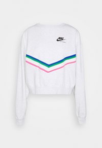 Lyhyt harmaa huppari, jossa on chevron-kuvio pinkeissä, vihreissä, sinisissä ja valkoisissa raidoissa, sekä musta Nike-logo yläselässä.