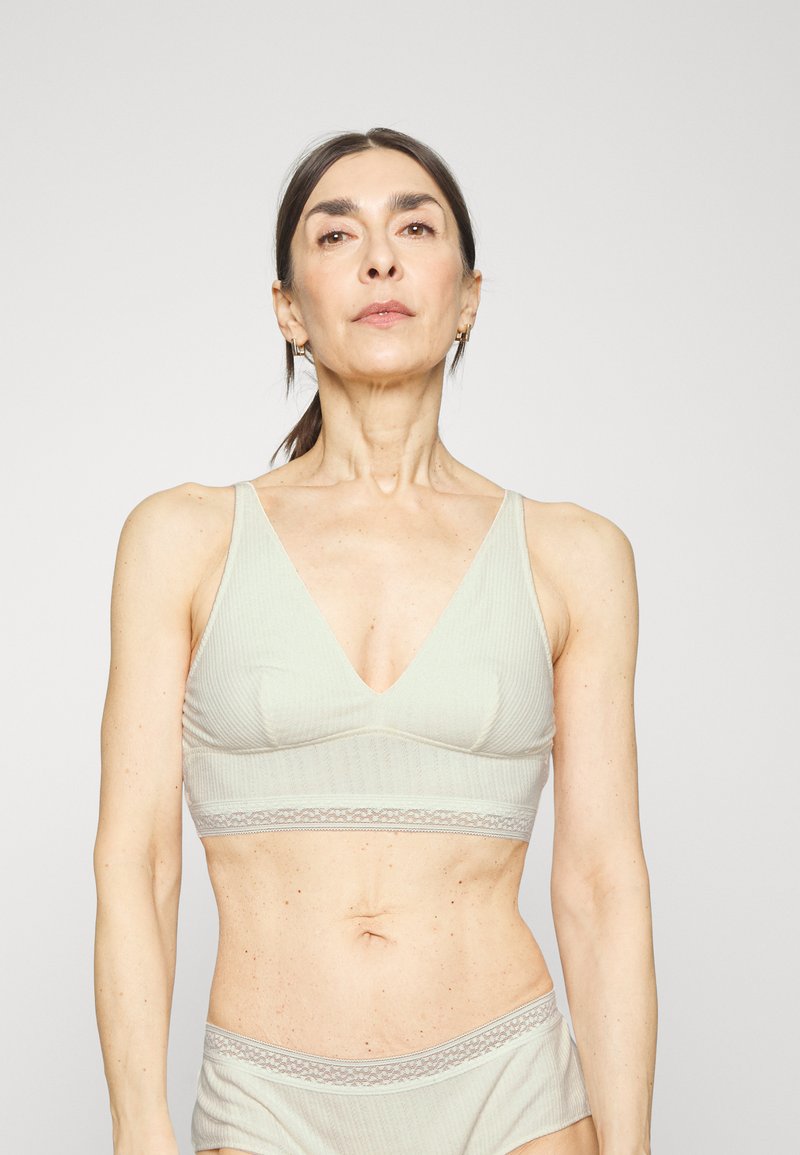 Bralette verde-claro com nervuras e design em V. Apresenta rendas na banda e uma textura suave para conforto.