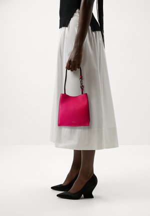 Sac en cuir rose vif avec une finition texturée, doté d'un haut arrondi et d'une sangle noire. Assorti à une jupe blanche et des talons compensés noirs.