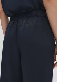 Navyblauwe broek met elastische tailleband en een gladde textuur, met een gathered tailleband en zachte stof, ontworpen voor comfort en gemak.