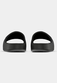 Crne gumene sandale na remen s otvorenim stražnjim dijelom, glatke teksture, zaobljenih rubova i minimalističkog dizajna. Nema vidljivih logotipa ni uzoraka.
