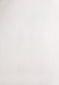 Texture de tissu beige clair uni avec un motif tissé subtil et des effets de lumière naturelle douce.