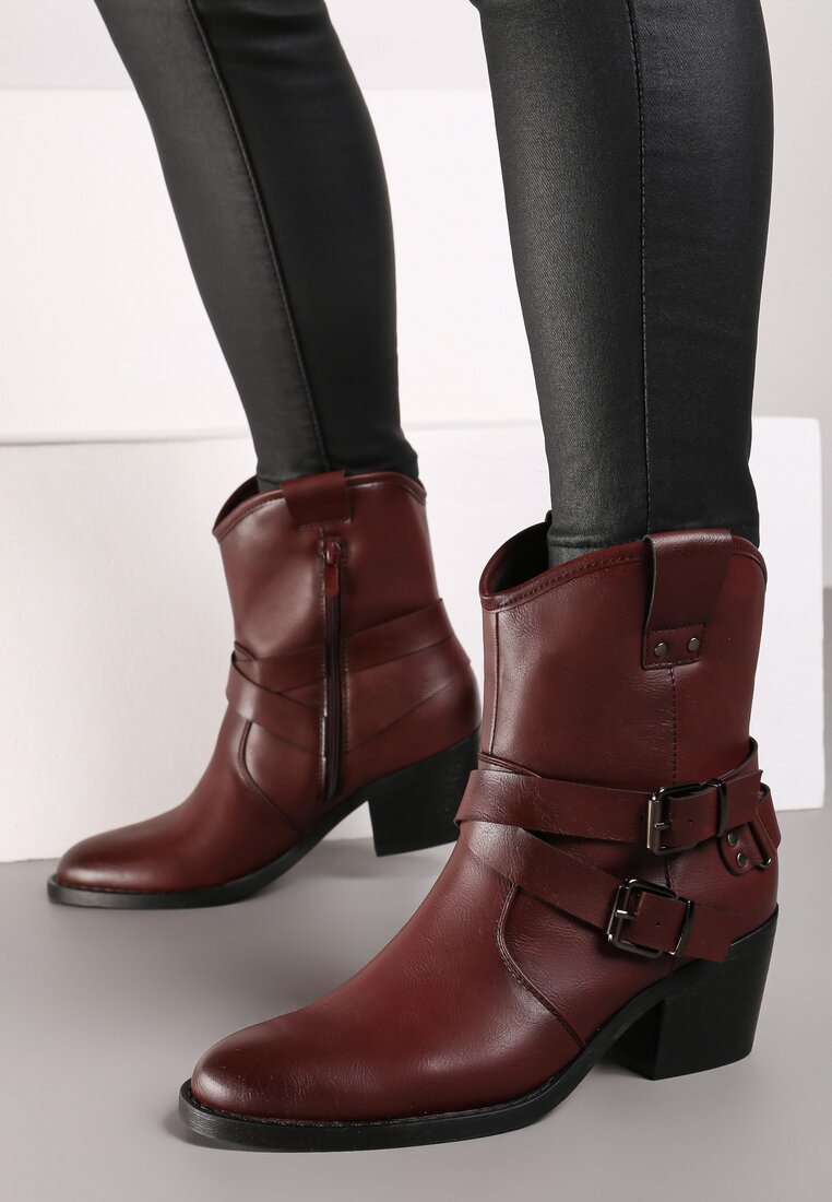 Bottes brunes en cuir à la cheville avec deux boucles décoratives, bout pointu et talon épais. Fini texturé et détail de fermeture éclair sur le côté.