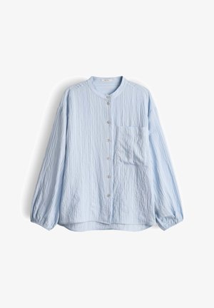 Blusa azzurro chiaro a maniche lunghe con colletto alla coreana, bottoni frontali, una tasca sul petto e tessuto dalla trama stropicciata.