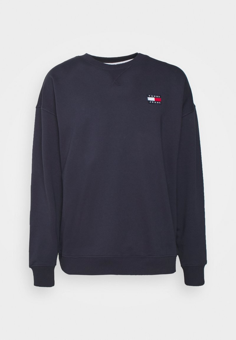 Navy sweatshirt made of cotton blend, featuring a crew neck, long sleeves, and a small logo patch with horizontal color stripes on the chest.