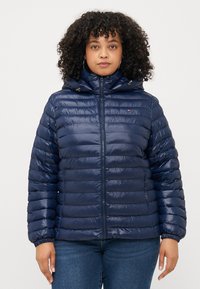 Marineblaue Pufferjacke mit Reißverschluss, Kapuze und elastischen Bündchen. Verfügt über ein gesteppte Design und ein kleines Logo-Akzent auf der Brust.