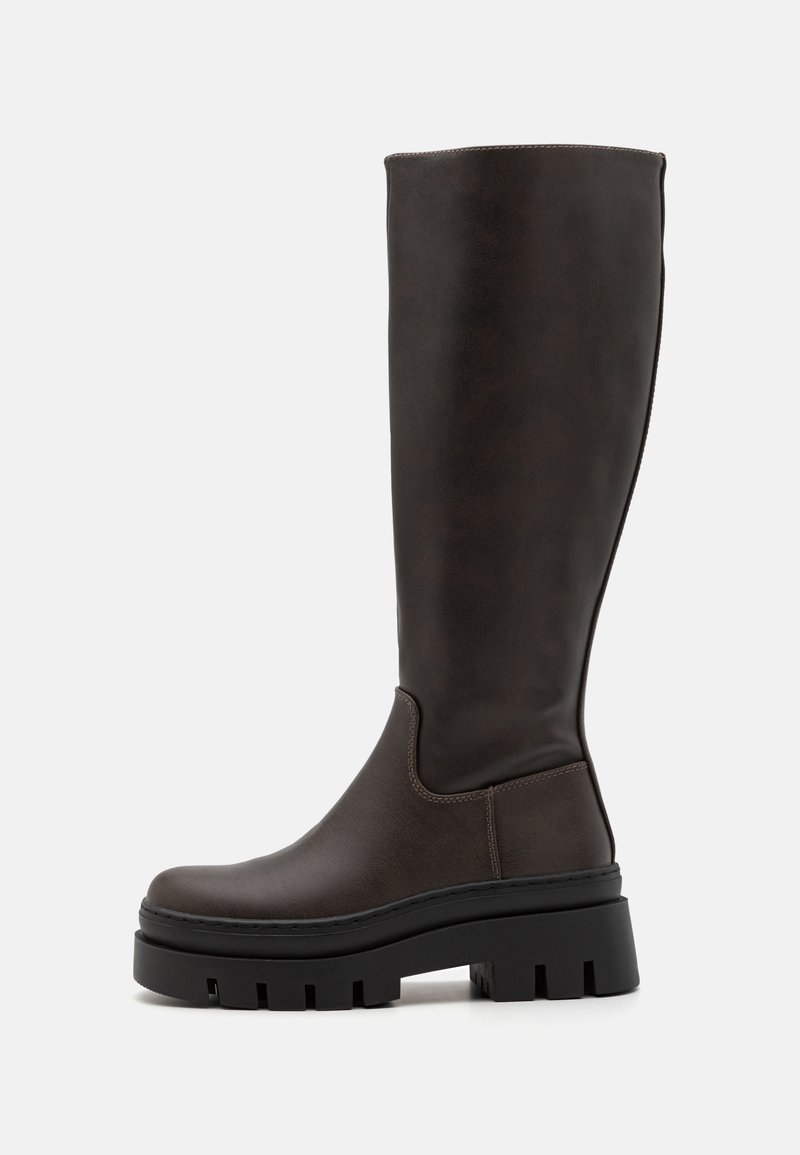 Bottes en cuir marron montantes jusqu'au genou avec une semelle noire épaisse et peu de détails de couture. Design épuré avec une texture lisse.