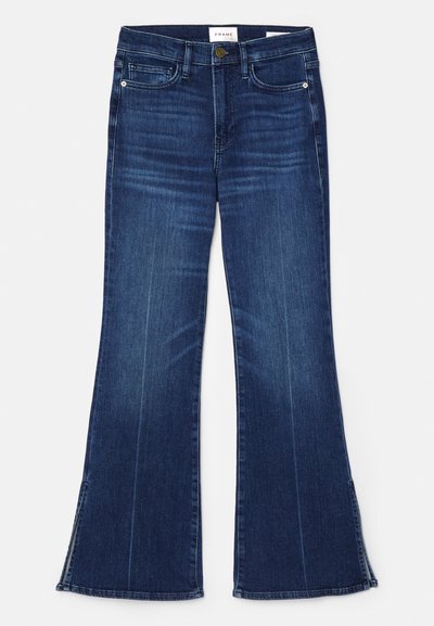 Dark blue flared jeans made from denim. Features a high waist, front pockets, and slit details at the hem.  Classic five-pocket design.