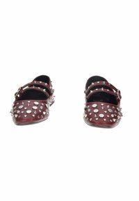 Ballerine Mary Jane in pelle rosso scuro con doppie cinghie, decorate con vari borchie e punte in argento sulla punta e sui lati.