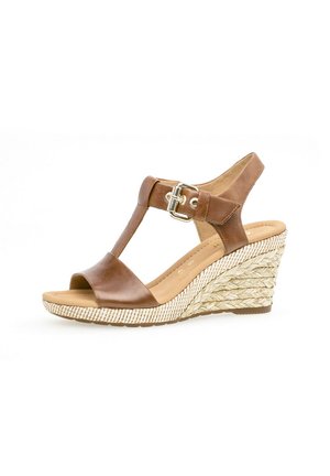 Brown leather wedge sandals with a T-strap design, featuring a buckle, woven jute-like accent on the wedge, and a smooth footbed.