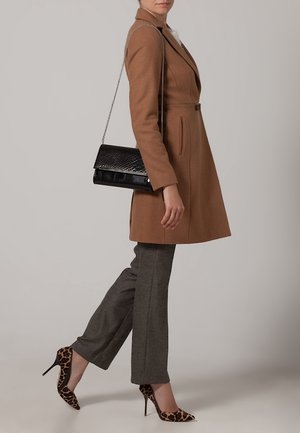 Manteau marron ajusté avec un bouton, pantalon gris et escarpins en imprimé léopard. Sac à main noir avec un design texturé et une bandoulière en chaîne.