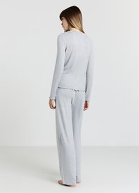 Ensemble de vêtements d'intérieur gris clair en tissu doux et texturé ; comprend un haut à manches longues avec des bords festonnés et un pantalon ample.