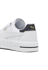 Fehér sneaker, texturált bőr felsőrésszel, kontrasztos fekete sarokkal, arany logóval és vastag fehér gumibetéttel, minimális fekete részletekkel.