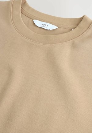 Beige Baumwollcrewneck-Sweatshirt mit geripptem Kragen und subtiler Textur. Das Etikett trägt die Aufschrift "NEXT" mit "REGULAR FIT" darunter.